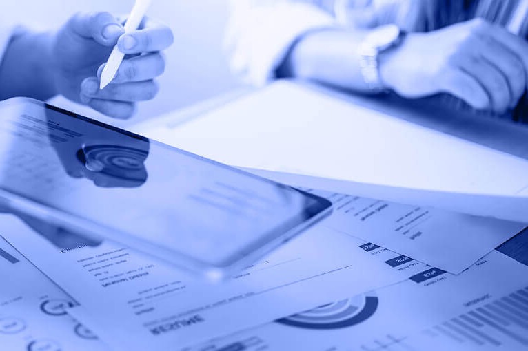 Blue Image of People Looking at Paper Documents and a Tablet