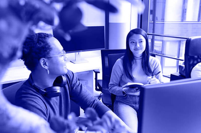 Blue Image of Two Women in a Meeting and Looking at a Computer